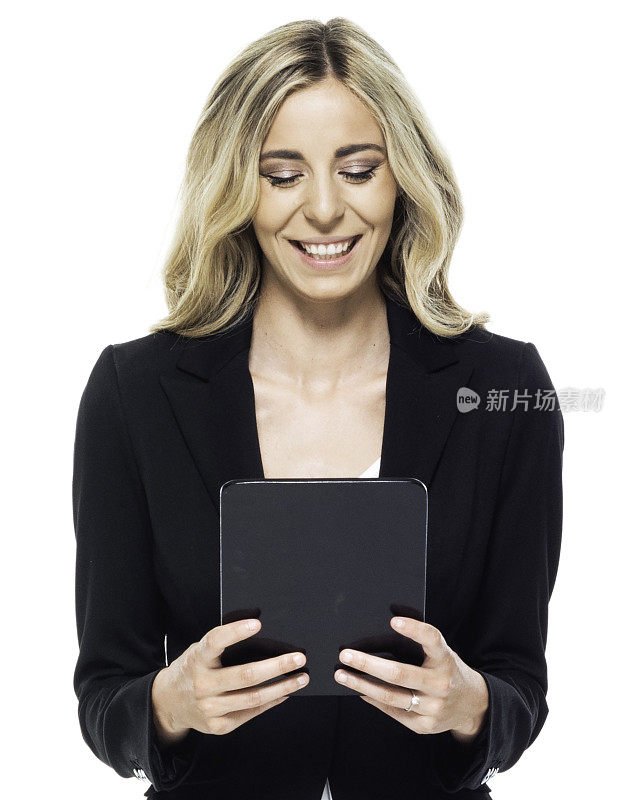 向下看/正面看/一个人/腰部以上的20-29岁的成年美丽的白人女性/年轻女性商人/女商人站着穿着套装谁是微笑/快乐/愉快的，并使用数字平板电脑